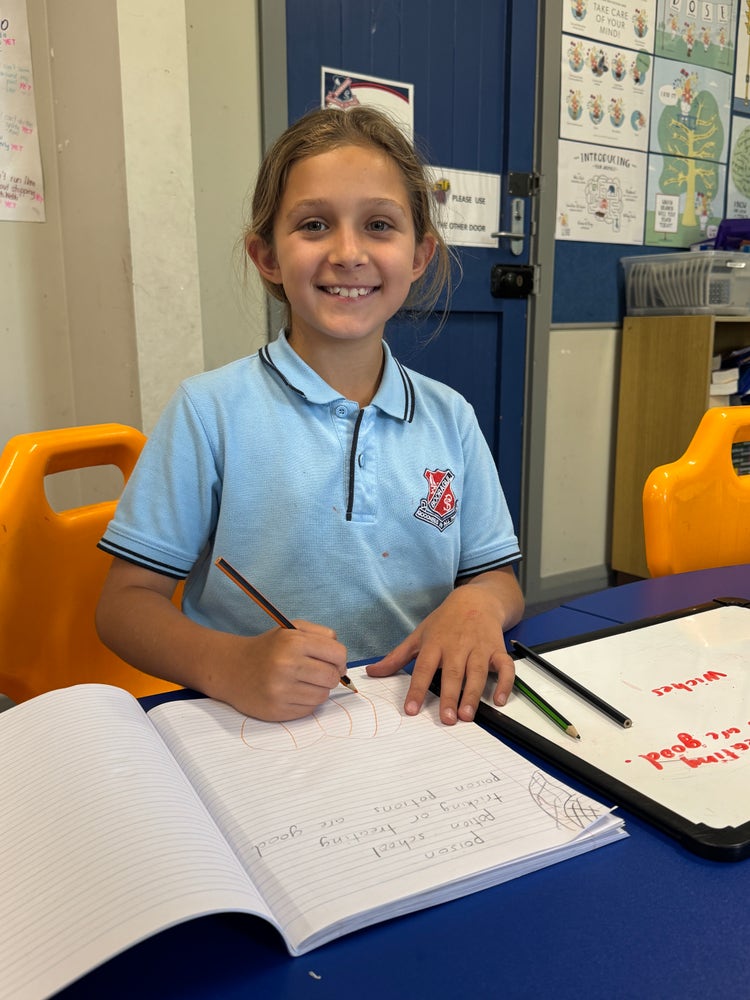 Girls sitting at desk with a pencil in her hand