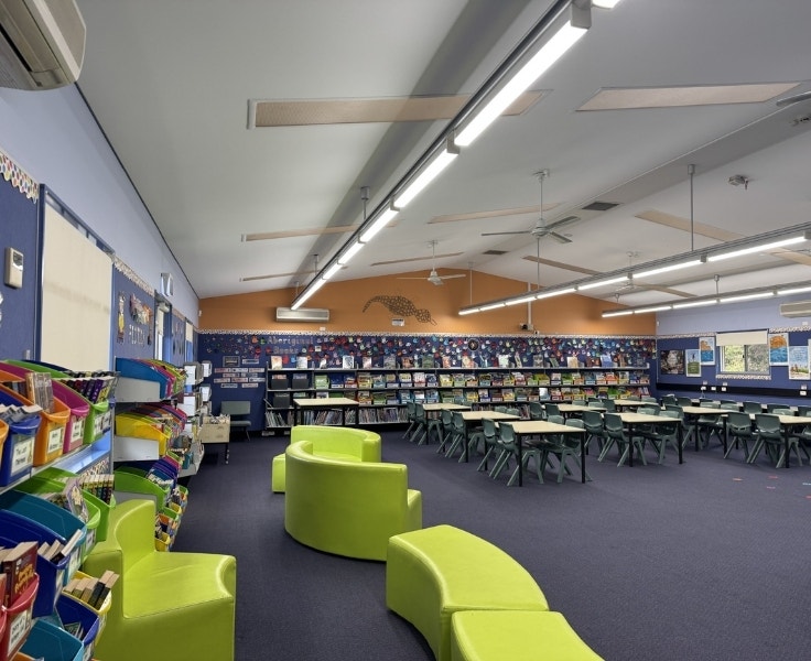 Library space with desks and chairs and green lounges