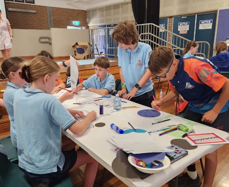 Five students looking down at a desk working