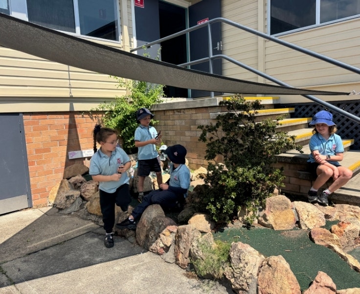 Four students sitting in a rock fairy garden