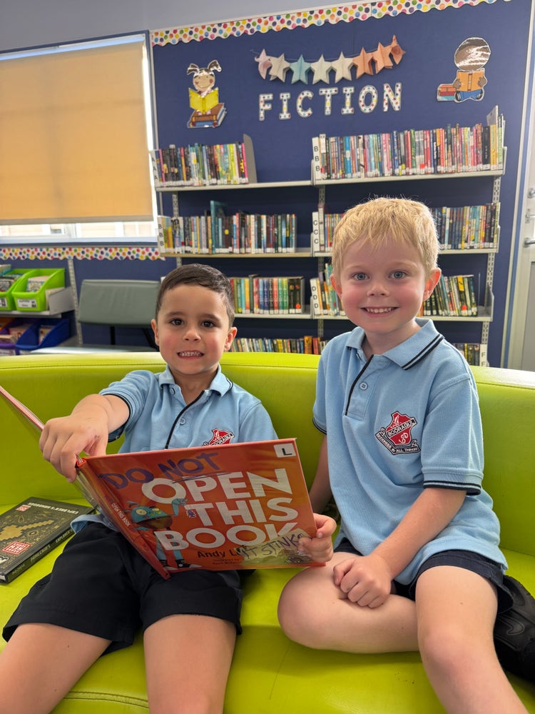 Two students sitting on a lounge with an open book